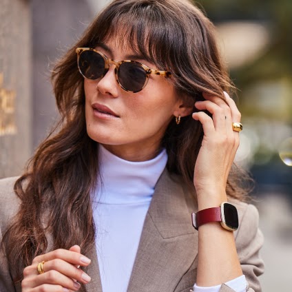 Fitbit Sense 2 in gold with burgundy leather band worn outdoors