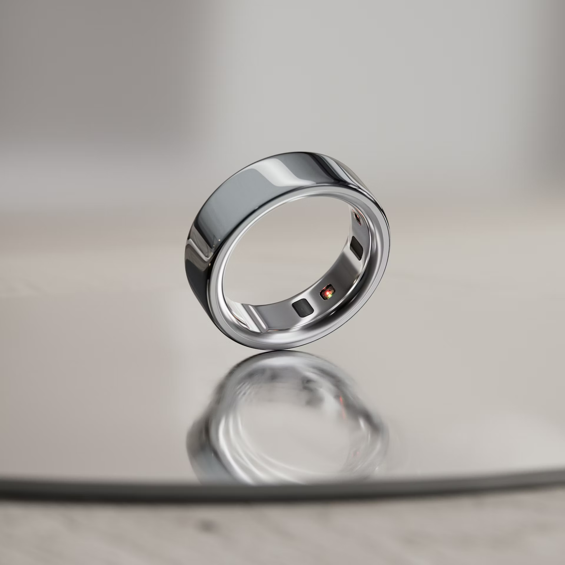 Oura Ring 4 Silver colorway on reflective glass surface