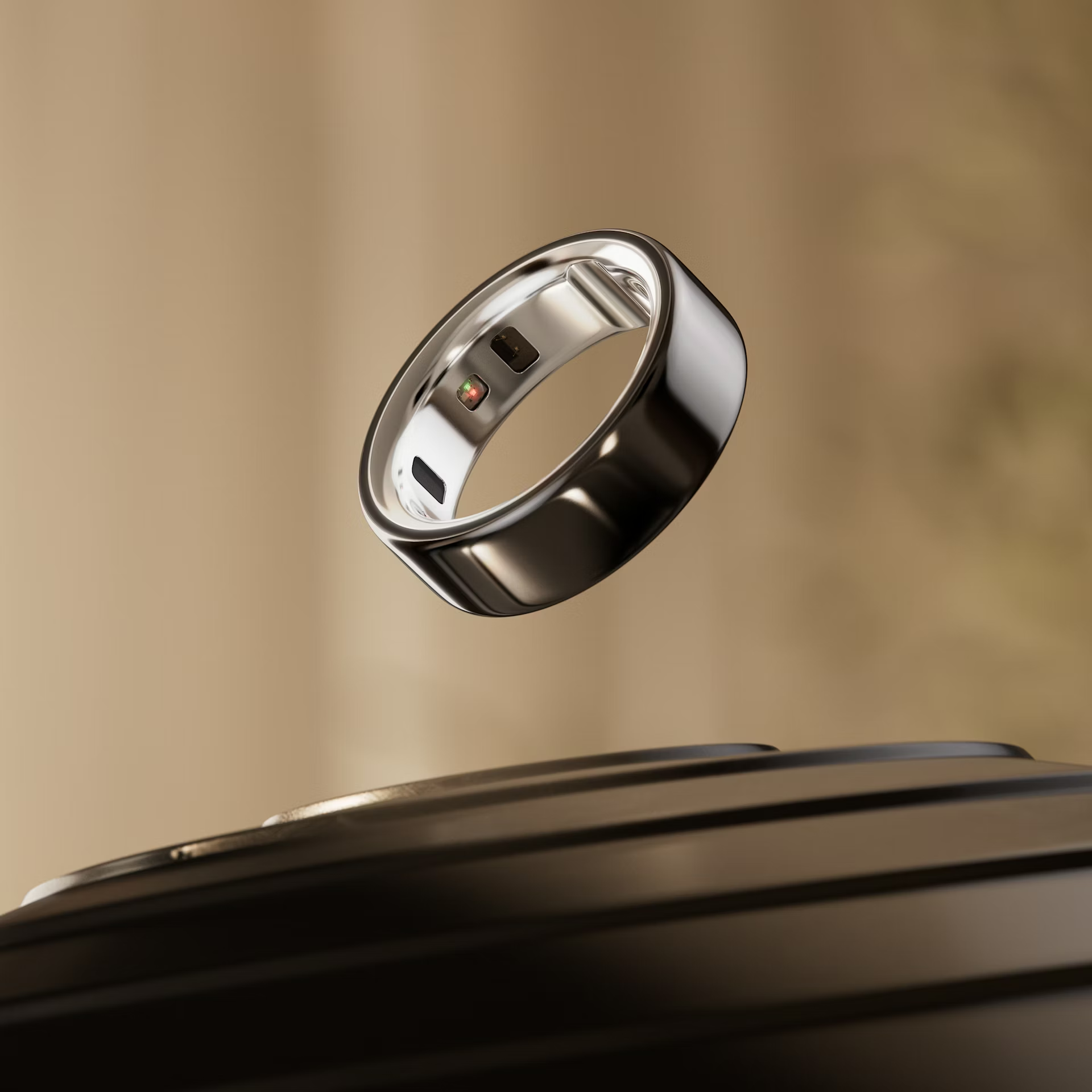 Oura Ring 4 Silver floating above dark surface warm background