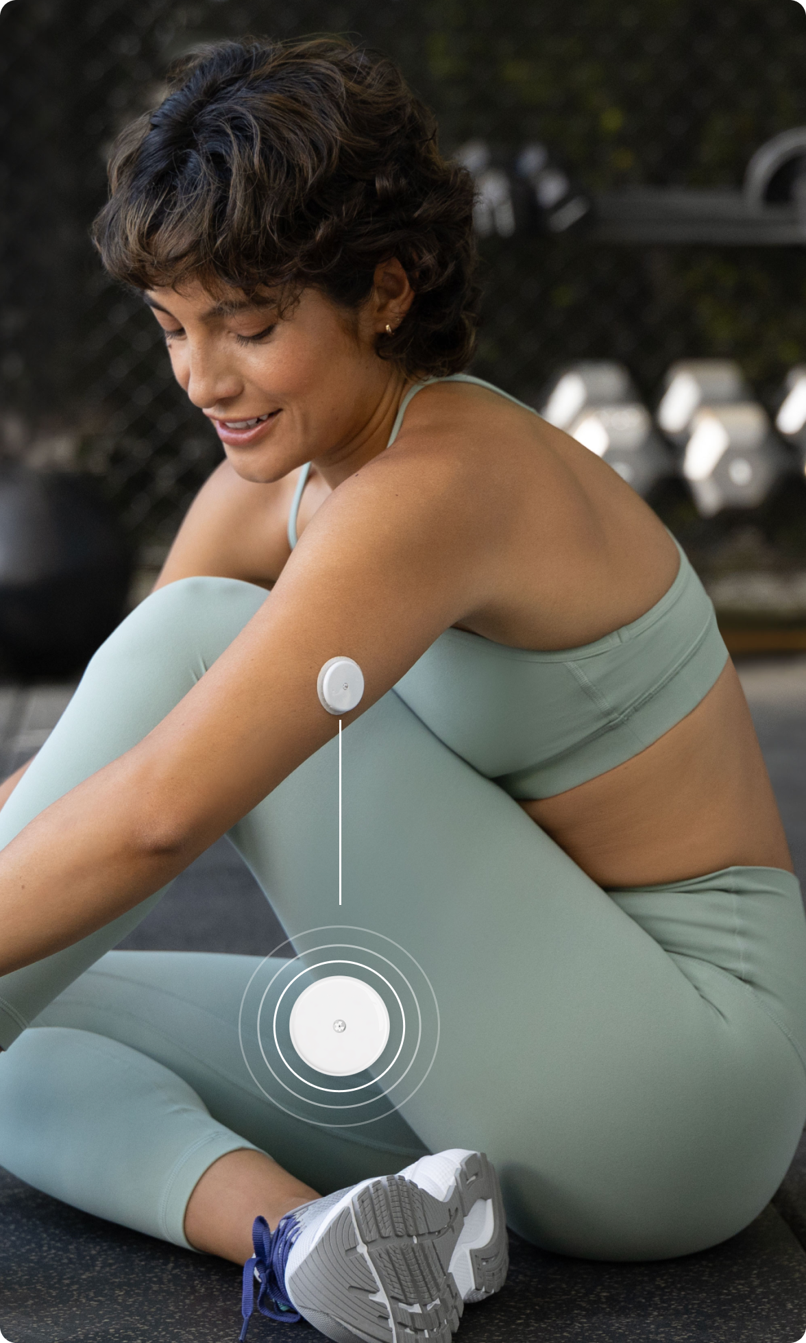 The white Lingo biosensor worn on the back of a womans upper arm in a gym